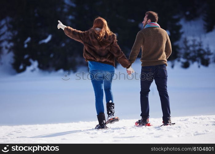 happy young couple having fun and walking in snow shoes. Romantic winter relaxation scene