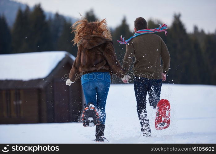 happy young couple having fun and walking in snow shoes. Romantic winter relaxation scene