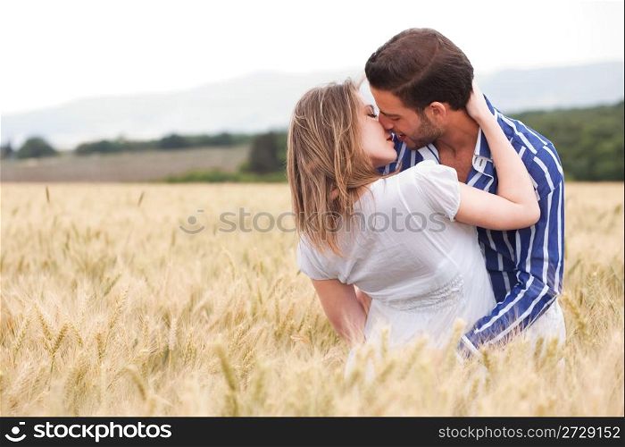 Happy young Couple hugging and kissing eachotherr in the meadow