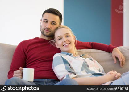 Happy young couple hugging and relaxing on sofa at home