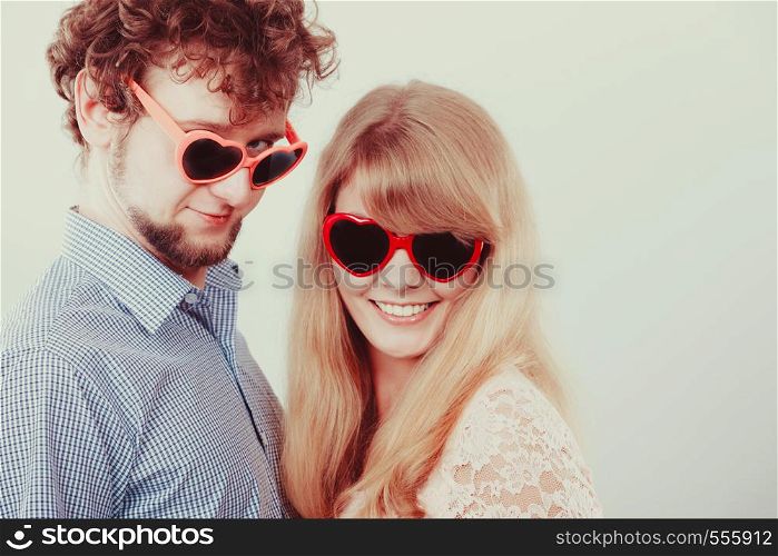 Happy young couple in heart shaped glasses. Smiling friends woman and man in studio.