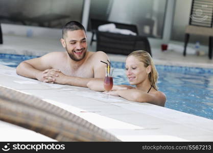 happy young couple in love have fun relax and drink coctail at indoor wellness swimming pool