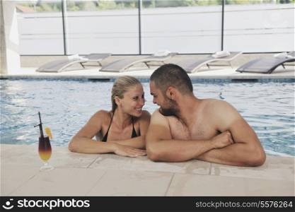 happy young couple in love have fun relax and drink coctail at indoor wellness swimming pool
