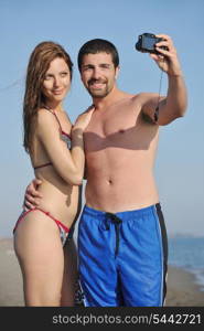 happy young couple in love taking amateur self portrait photos on beach