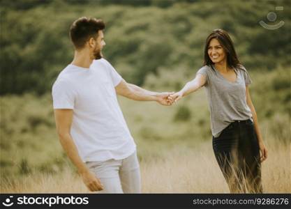 Happy young couple in love walking through grass field on a summer day