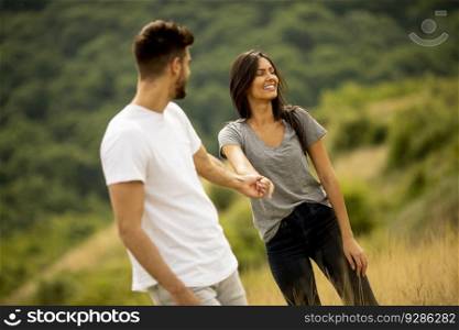 Happy young couple in love walking through grass field on a summer day