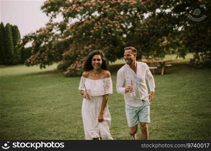 Happy young couple is enjoying the beautiful surroundings of a garden with glasses of fresh lemonade