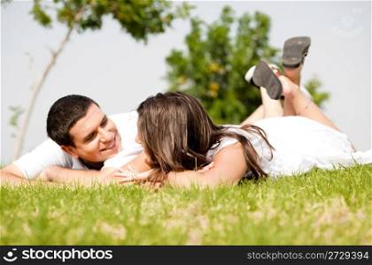 happy young Couple lie down on grass look each other