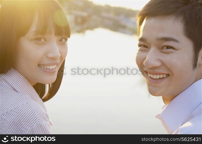 Happy Young Couple Looking at the Camera by a River