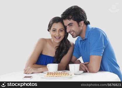 Happy young couple looking away while having coffee against over background