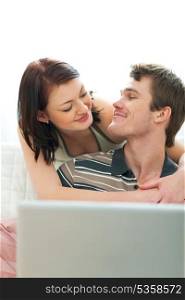Happy young couple looking in laptop