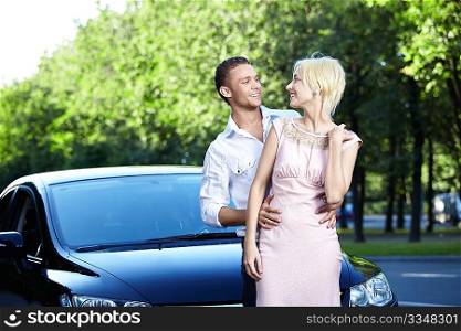 Happy young couple next to cars