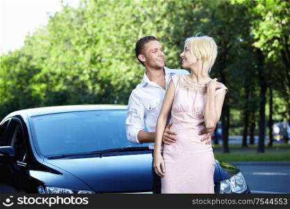 Happy young couple next to cars