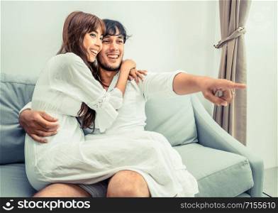 Happy young couple on sofa in home living room in the morning.. Happy young couple watching TV in living room.