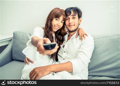 Happy young couple on sofa in home living room in the morning.. Happy young couple watching TV in living room.