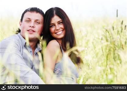 Happy young couple outdoors, two lovers on grass field. Happy lovers on grass field