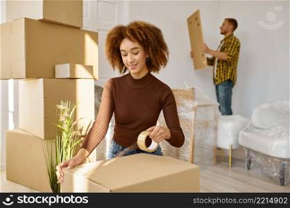 Happy young couple packing stuff into carton boxes. Home moving, repair and real estate concept. Young couple packing stuff into carton boxes