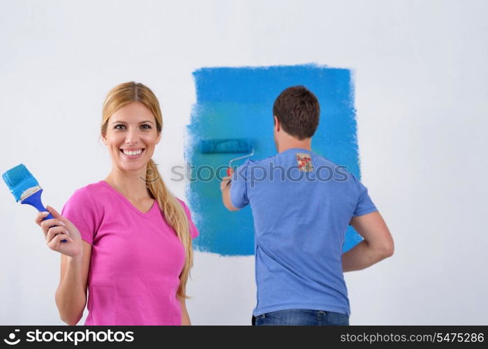 happy young couple paint in green and blue color white wall of their new home