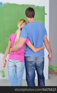 happy young couple paint in green and blue color white wall of their new home