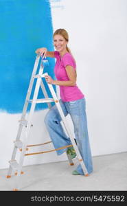 happy young couple paint in green and blue color white wall of their new home