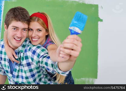 happy young couple paint in green and blue color white wall of their new home