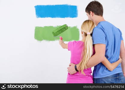 happy young couple paint in green and blue color white wall of their new home