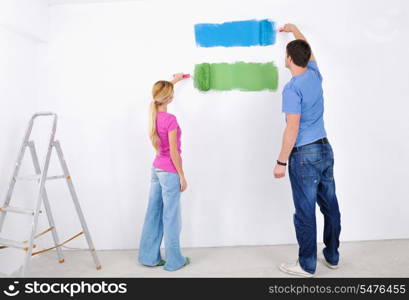 happy young couple paint in green and blue color white wall of their new home