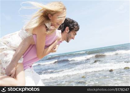 Happy young couple playing on the beach