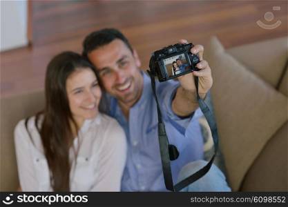 happy young couple playing with digital camera at home