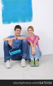 happy young couple relax after painting white wall in green and blue color in their new home