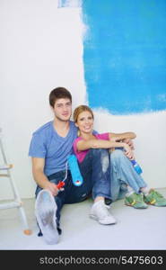 happy young couple relax after painting white wall in green and blue color in their new home