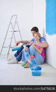 happy young couple relax after painting white wall in green and blue color in their new home