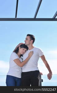 happy young couple relax on balcony outdoor with ocean and blue sky in background