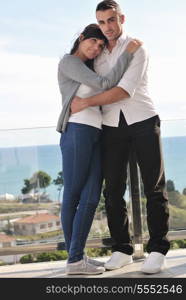 happy young couple relax on balcony outdoor with ocean and blue sky in background