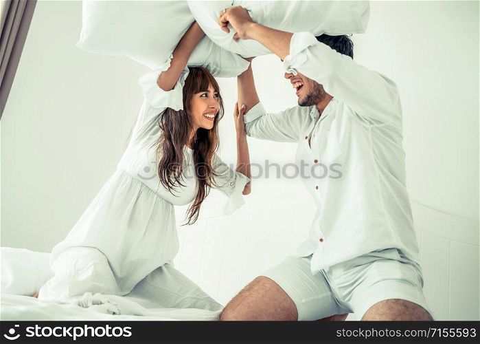Happy young couple relaxing at home in the morning.. Young couple do pillow fighting in bedroom.