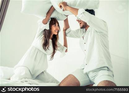 Happy young couple relaxing at home in the morning.. Young couple do pillow fighting in bedroom.