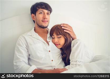Happy young couple relaxing in home bedroom after waking up in the morning.