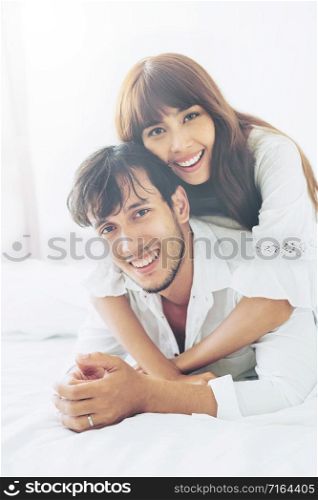 Happy young couple relaxing in home bedroom after waking up in the morning.. Happy young couple relaxing in the home bedroom.