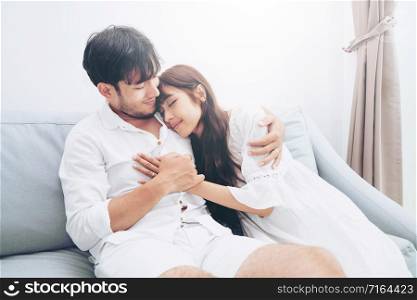 Happy young couple relaxing on sofa in home living room in the morning.. Happy young couple relaxing on sofa in living room