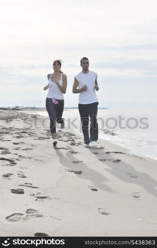 happy young couple running and jogging on beach at early morning