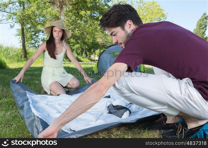 happy young couple setting up their tent at camping site