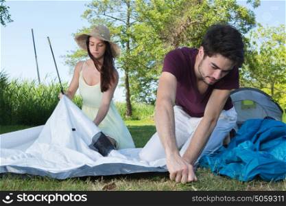 happy young couple setting up their tent at camping site