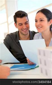 Happy young couple signing property purchase contract