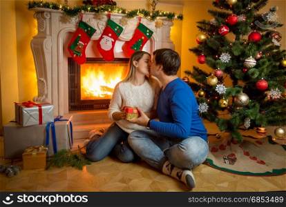 Happy young couple sitting at the fireplace and kissing