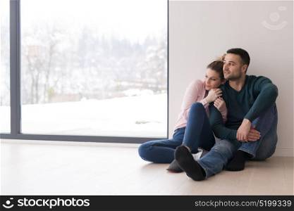 happy young couple sitting near window at home on cold winter day