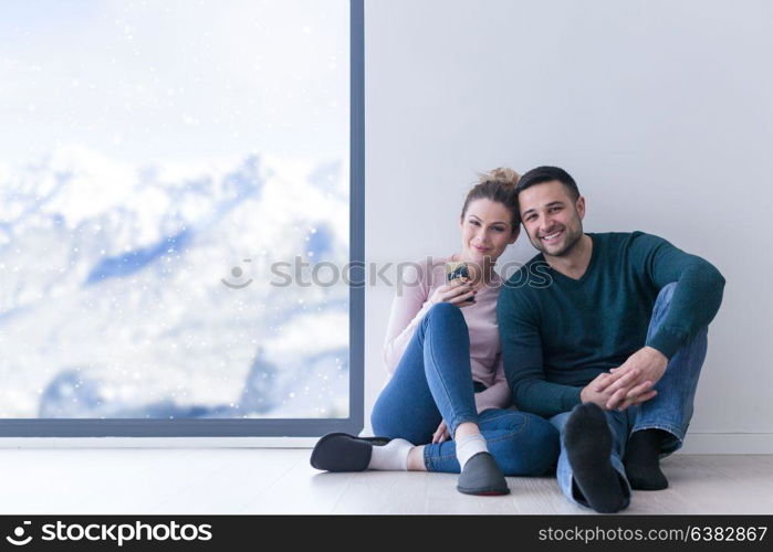 happy young couple sitting near window at home on cold winter day