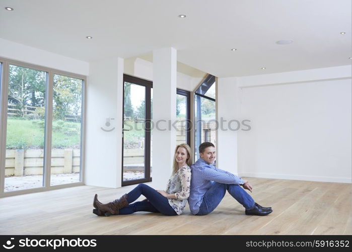 Happy Young Couple Sitting On Floor In New Home