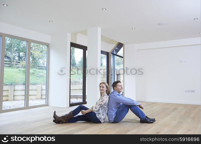 Happy Young Couple Sitting On Floor In New Home