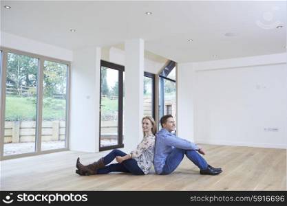 Happy Young Couple Sitting On Floor In New Home