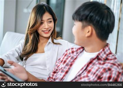Happy Young couple sitting on sofa in living room at home use tablet with happiness together, happy family concept
